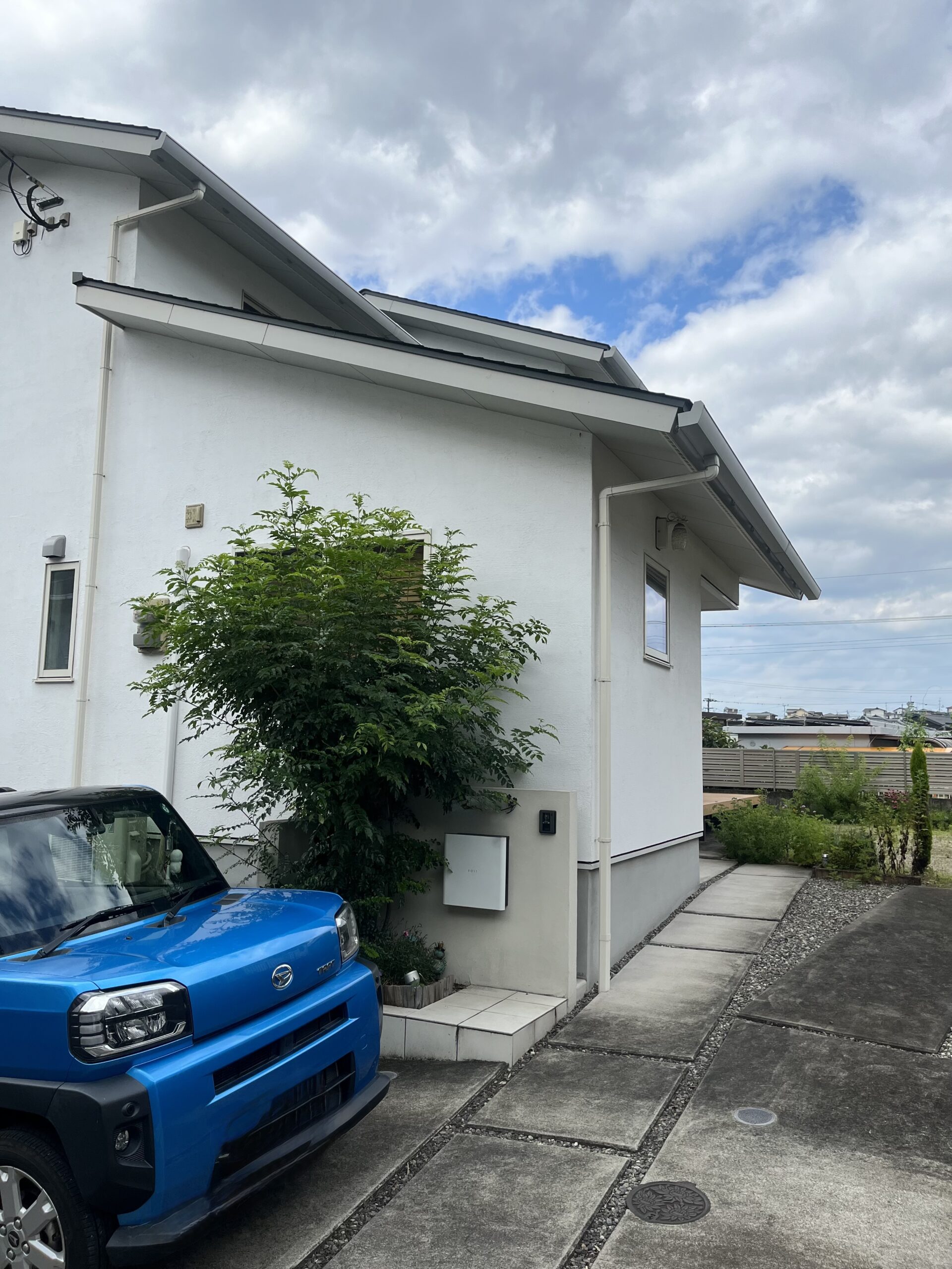 サロンの外観。白い壁の建物と、玄関前の駐車スペース
